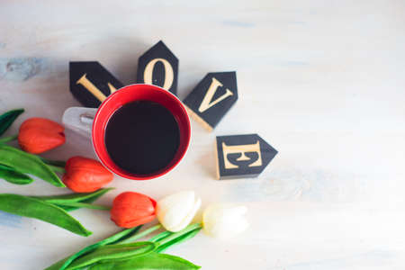 Mug of coffee and tulips on rustic background