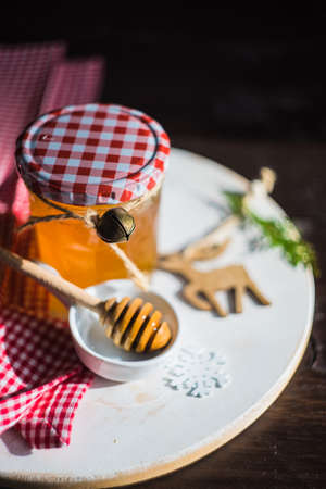 Christmas holiday concept with organic honey decorated with fir tree and jinglebells on rustic backgroundの写真素材