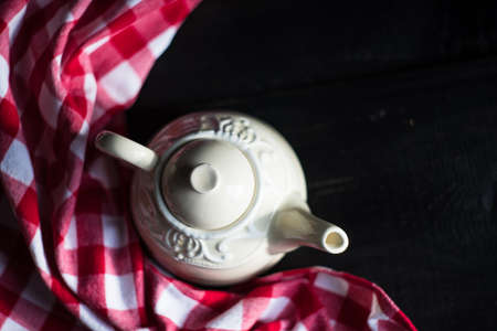Vintage tea pot and red rustic napkin on wooden tableの写真素材