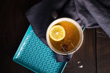 Cup of tea with lemon on dark wooden table with copyspace