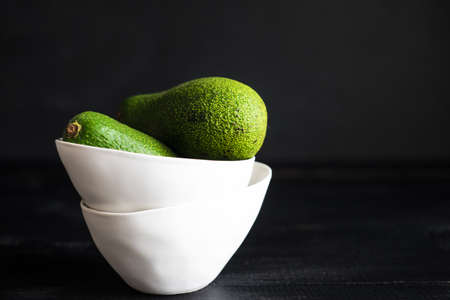Organic food concept with ripe avocado on dark wooden table with copyspace