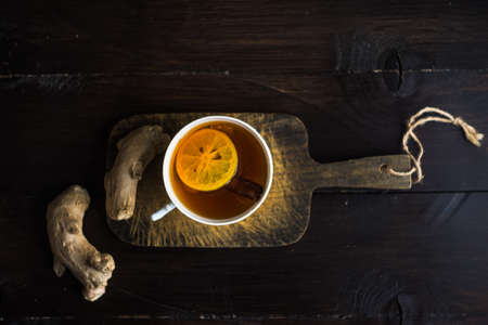 Cup of tea with ginger, lemon and honey on rustic wooden table with copyspace