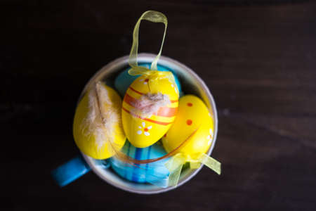 Easter holiday concept with colored easter eggs in a bowl on dark wooden background with copyspaceの写真素材