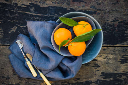 Ripe organic tangerines on rustic plate with knife for citrus on wooden table with copyspaceの写真素材