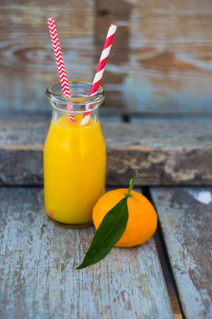 Ripe tangerines and bottle of fresh tangerines juice on rustic background with copyspaceの写真素材