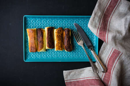 Stuffed pancakes crepes with meat and cream sauce on dark wooden table with copyspace