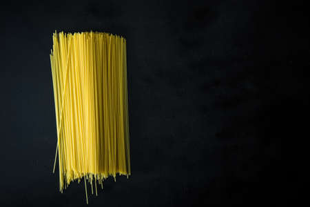 Thin long spaghetti on black background as a food background concept.の写真素材