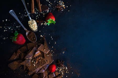 Dark chocolate pieces crushed on dark wooden table, spices like a cinnamon and anise star as a culinary concept with copy space, top viewの写真素材