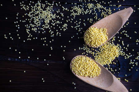 organic raw millet seeds in a rustic bowl on wooden table with copyspaceの写真素材