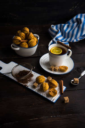 Nut shaped holiday cookies with armored cow and cupof tea with lemon on dark wooden table with...