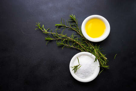 Rosemary herb, sea salt and olive oil in ceramic bowls on rustic wooden background with copyspaceの写真素材