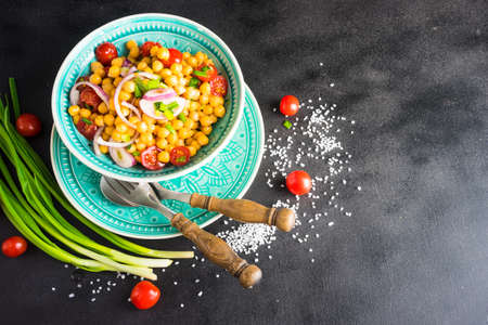 Homemade spicy vegetarian stew with chickpeas and vegetables on rustic wooden background with copy...