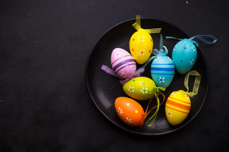 Easter festive table setting with plate, napkin and silverware decorated with colored eggs on rustic...