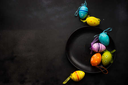 Easter festive table setting with plate, napkin and silverware decorated with colored eggs on rustic table with copyspaceの写真素材