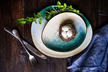 Table setting for holiday Easter dinner on dark wooden table with copy space