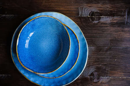 Rustic table setting with ceramic plates, napkin and silverware on dark wooden tableの写真素材