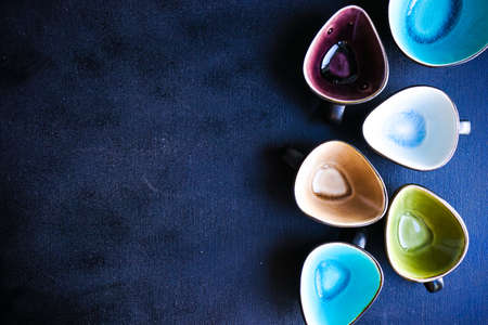 Empty ceramic rustic cups different colors on dark wooden table with copy spaceの写真素材