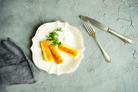 Breakfast concept: stuffed pancakes crepes with meat and cream sauce and cup of coffee on concrete table with copyspaceの写真素材