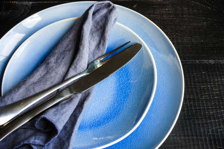 Rustic table setting with ceramic plates, napkin and silverware on dark wooden tableの写真素材