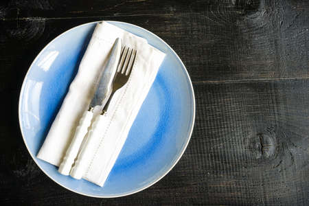 Rustic table setting with ceramic plates, napkin and silverware on dark wooden tableの写真素材