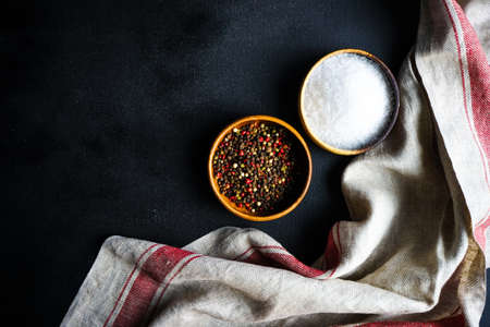Bowl with pepper and sea salt on dark wooden tableの写真素材