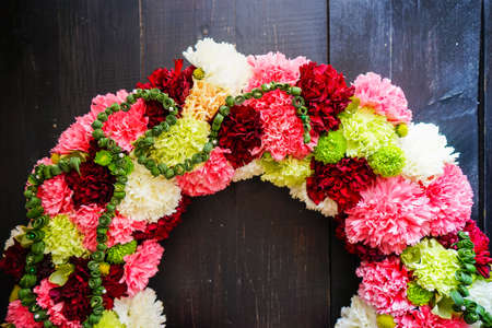 circlet of carnation flowers on dark wooden background with copyspaceの写真素材