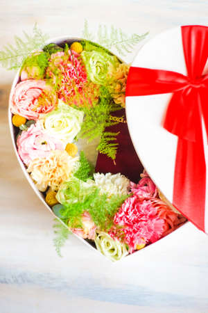 Heart shaped gift box full of anemone flowers on dark background with copy spaceの写真素材