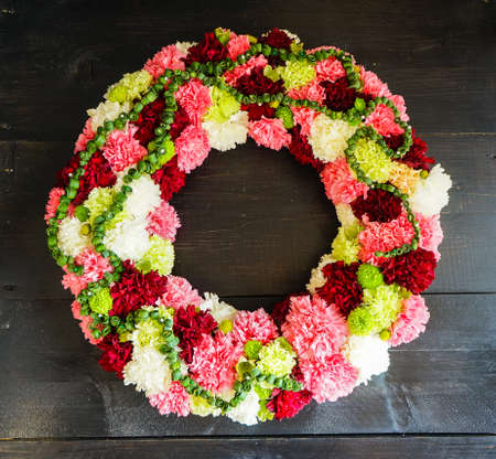 circlet of carnation flowers on dark wooden background with copyspaceの写真素材