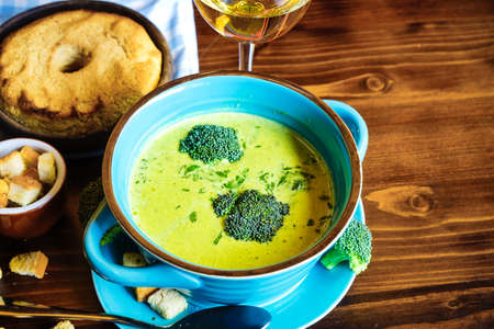 Rustic dinner set with healthy broccoli cream soup on dark wooden tableの写真素材