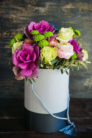Beautiful bouquet in vintage box with fresh anemone, roses, brassica, and antirrhinum flowersの写真素材