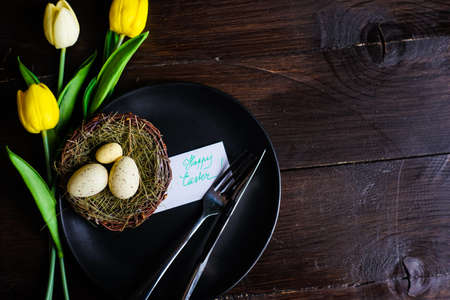 Table setting for holiday Easter dinner decorated with tulips and eggs