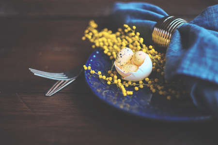 Easter holiday card with colored easter eggs and rustic tableware on dark wooden table with copy spaceの写真素材