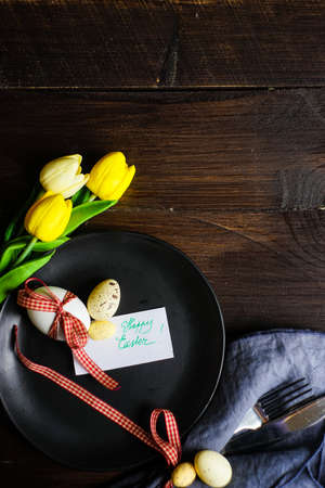 Table setting for holiday Easter dinner decorated with tulips and eggsの写真素材