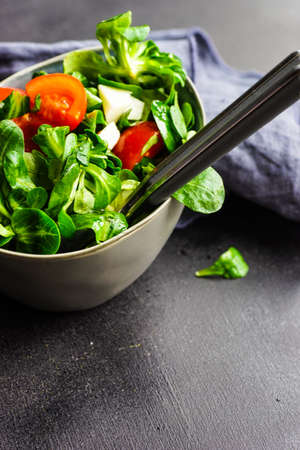 Healthy food concept - fresh corn salad leaves, cheese annd tomatoes on rustic background wih copyspaceの写真素材