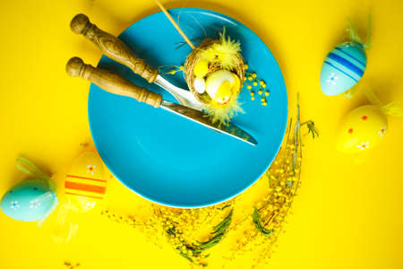 Easter holiday card with colored easter eggs and rustic tableware on bright background with copy spaceの写真素材