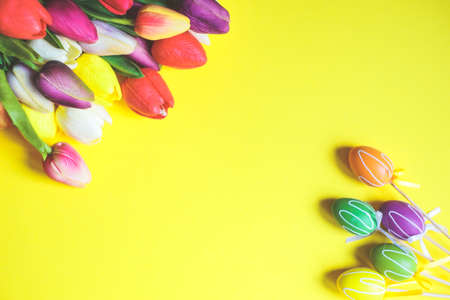 Spring Easter card with tulip flowers and eggs on bright yellow background with copy spaceの写真素材