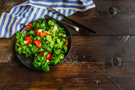 Healthy food concept - fresh corn salad leaves, cheese annd tomatoes on rustic background wih copyspaceの写真素材