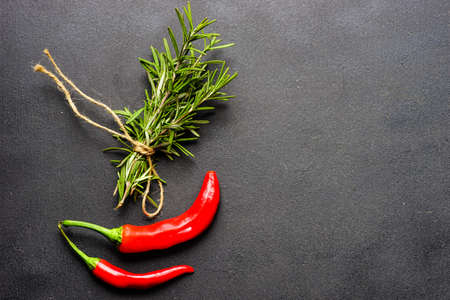 Organic food cooking concept with fresh rosemary and red hot chilli peppers on dark background with copyspaceの写真素材