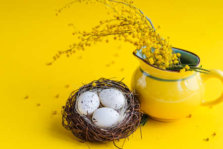 Easter holiday card with yellow mimosa flower and holiday decoration on bright background with copy spaceの写真素材