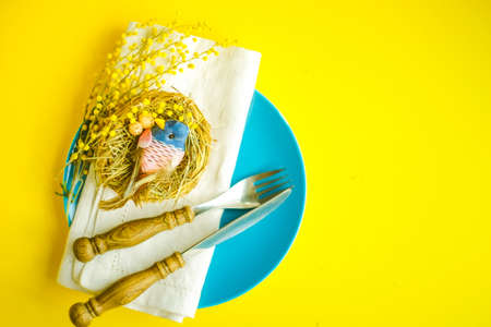 Easter holiday card with colored easter eggs and rustic tableware on bright background with copy...