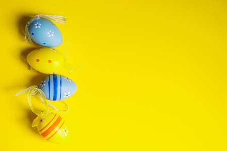Spring Easter card with colored eggs on bright yellow background with copy spaceの写真素材