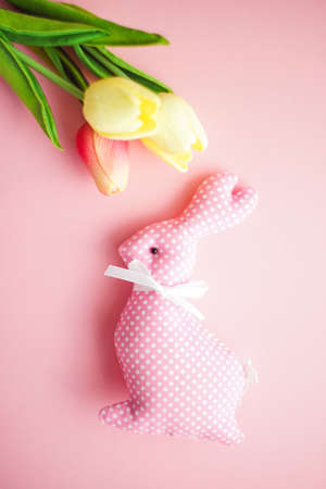 Spring Easter card with tulip flowers and eeaster bunny on pink  background with copy spaceの写真素材