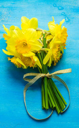 Spring concept with bright yellow daffodils on wooden table with copyspaceの写真素材