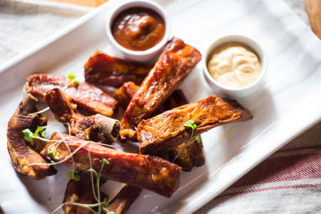 juicy barbeque pork ribs with ketchup sauce on wooden tableの写真素材