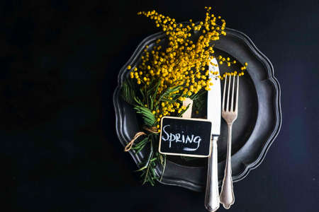 Spring table setting with bright yellow mimosa flowers