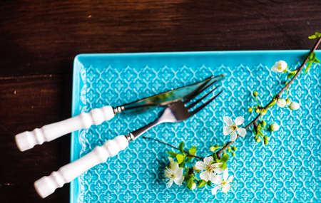 Spring floral concept with blooming cherry tree branches and serving with rustic tablewares on dark wooden tableの写真素材