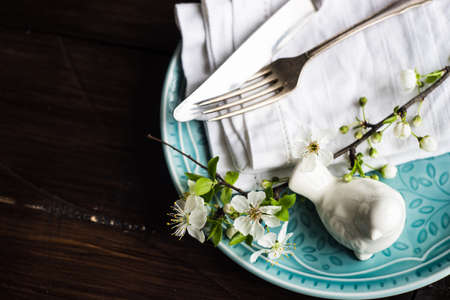 Spring floral concept with blooming cherry tree branches and serving with rustic tablewares on dark...