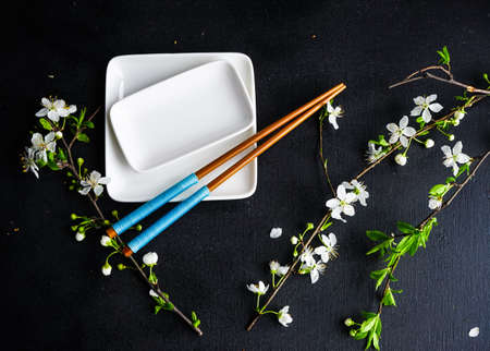 Spring floral concept with blooming cherry tree branches and serving with rustic tablewares on dark wooden tableの写真素材