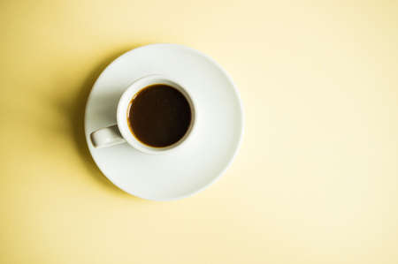 Coffee concept with cup of coffee on yellow background with copy space