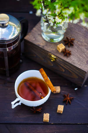 Tea pot, cup of tea, blooming cherry and spices on rustic wooden tableの写真素材